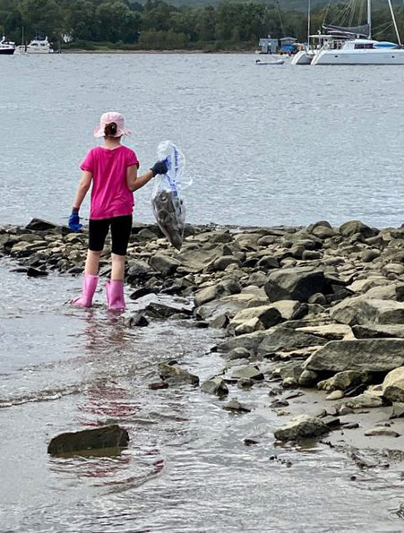 Young person picking up trash along the shoreline